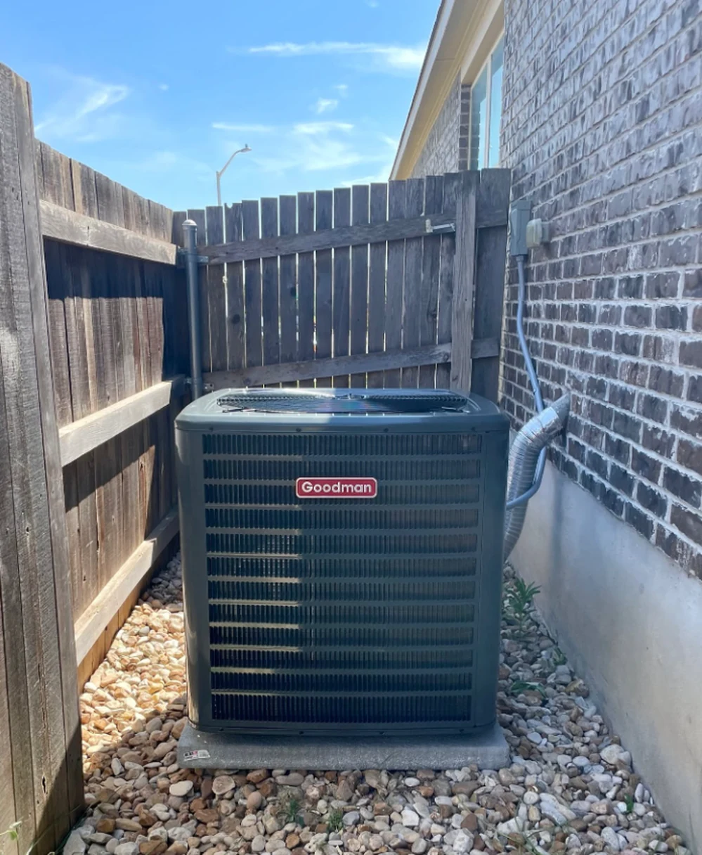 Goodman condenser installed on a pad alongside a Buda home